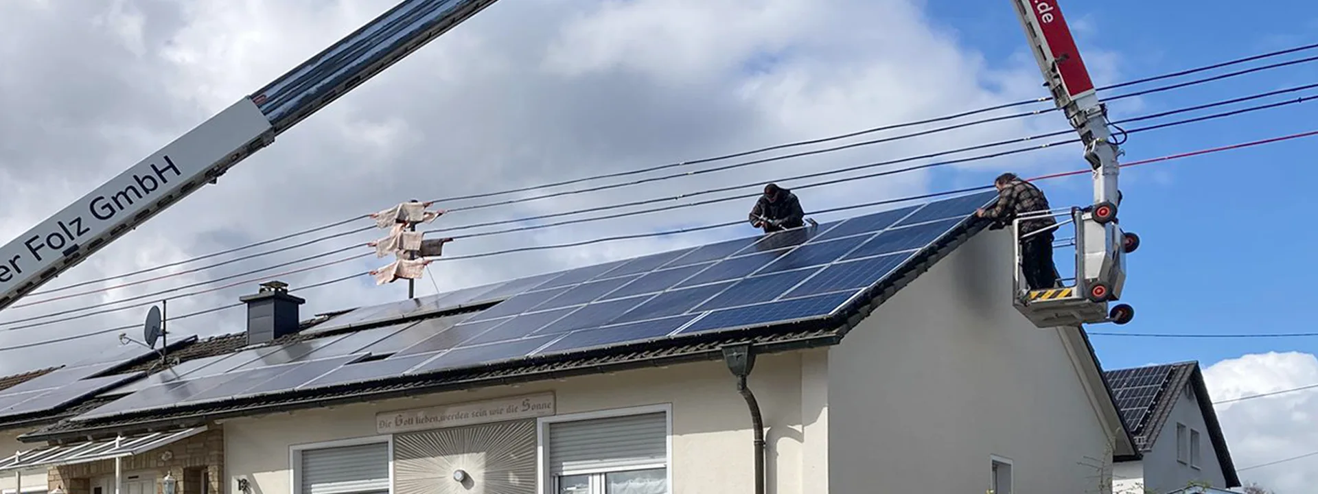 Zwei Arbeiter montieren Taubenschutz auf Dach, erreichbar über Hubarbeitsbühne neben Kran